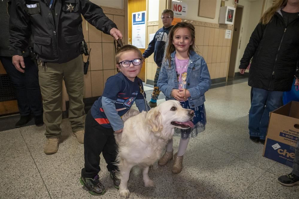   Students posing with River, a therapy dog at Lura Sharp Elementary during Family Fun Night!